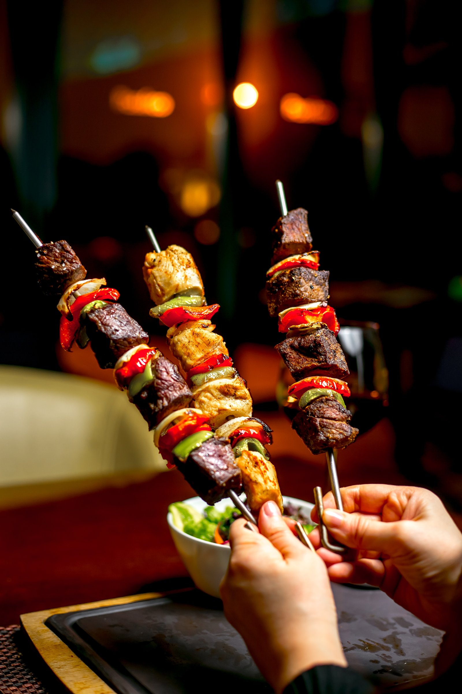 Hands holding shish kebab with colorful bell peppers